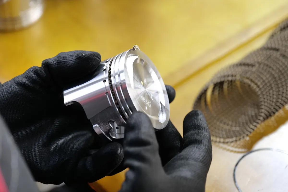 Bàn tay đeo găng cầm quả piston mới