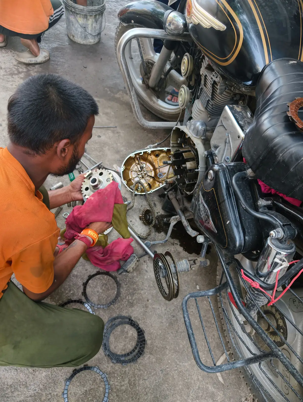 Người thợ tháo rời động cơ xe máy ngay trên nền nhà